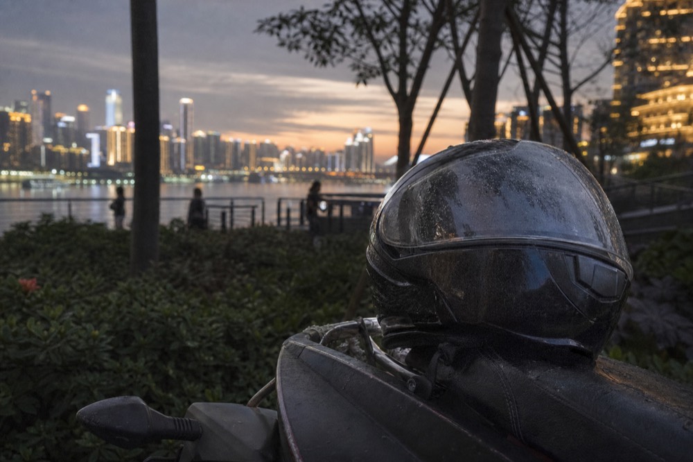 A motorcycle helmet resting on a motorcycle seat with city lights blurred in the background