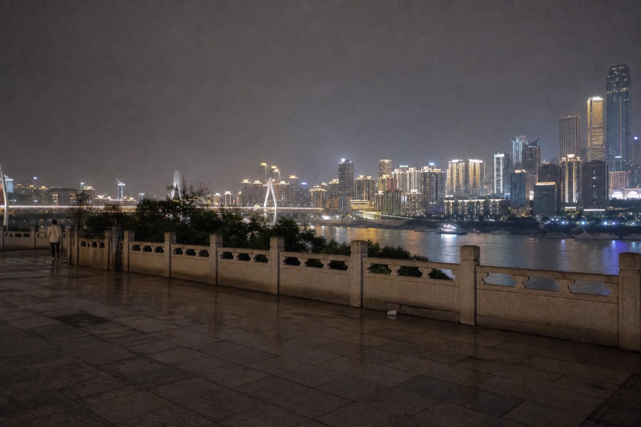 Illuminated high-rise towers of Chongqing rising above a river at night