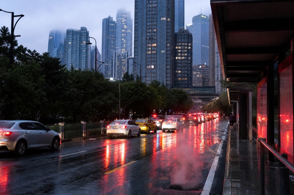 Taxi and bus lane on a lit city street with high-rise towers above at night