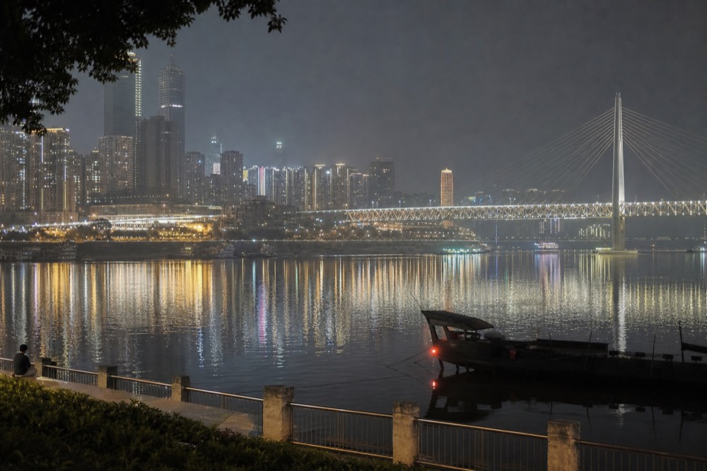 Night skyline of Chongqing towers reflected in the wide Yangtze river, bridges lit along the water