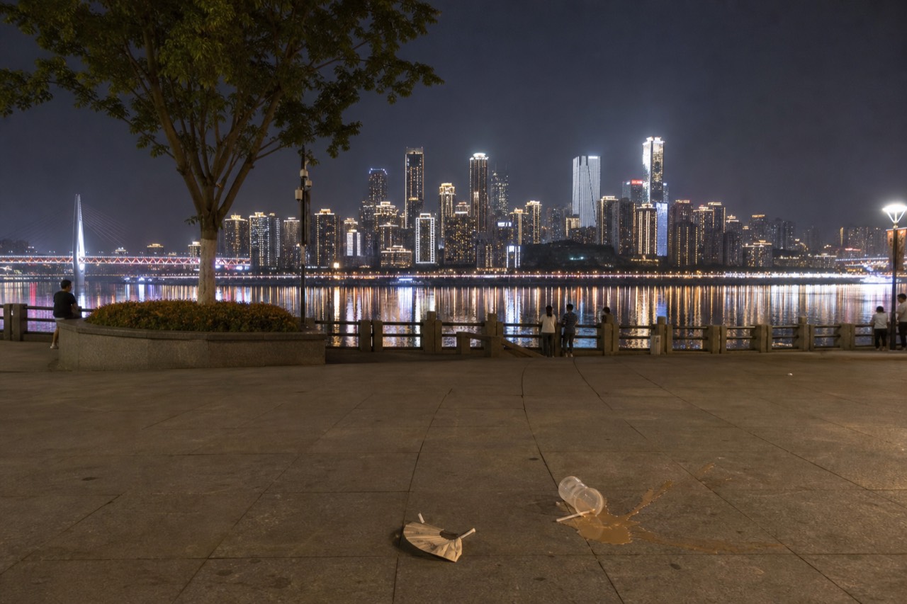 Night view of a brightly lit riverside city skyline reflected in a wide dark river