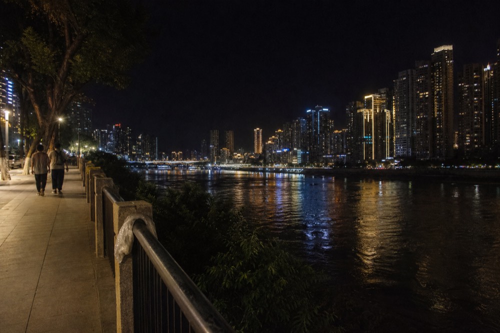 Tower lights reflecting across a wide river with a dark sky above