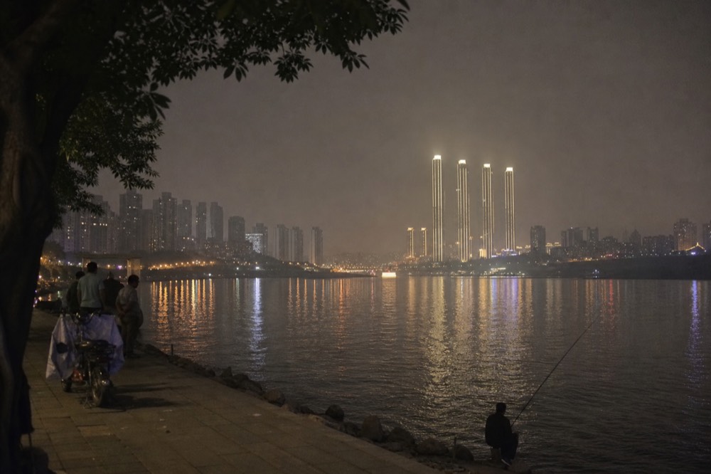 City skyline with illuminated towers seen across a wide river at night