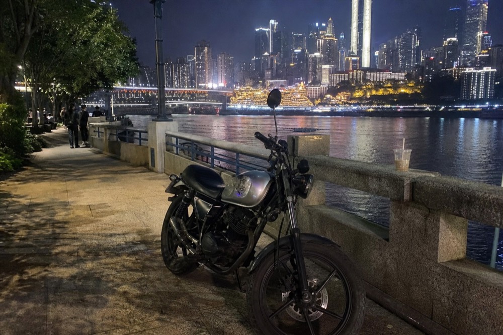 Motorcycle parked beside a lit riverside promenade at night