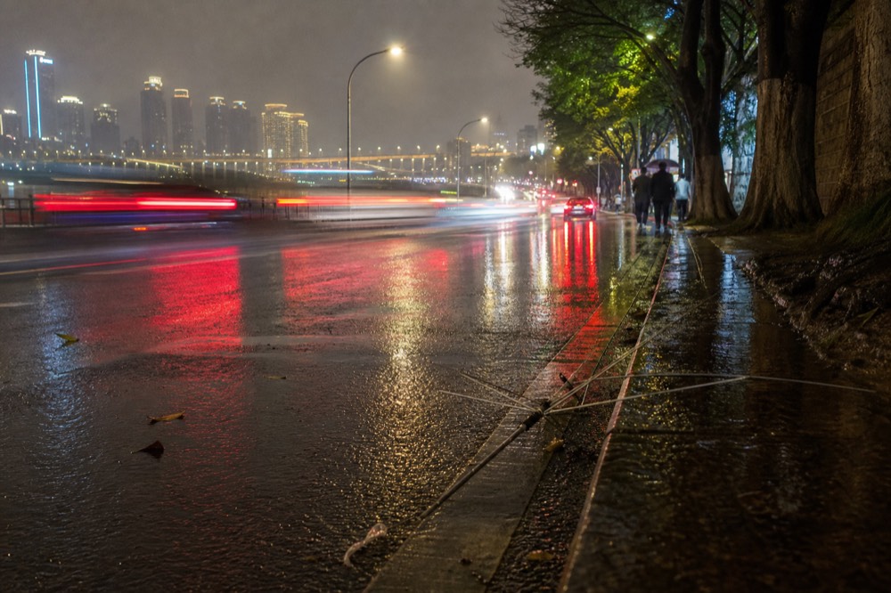 Night city street with neon reflections on wet pavement and traffic light trails