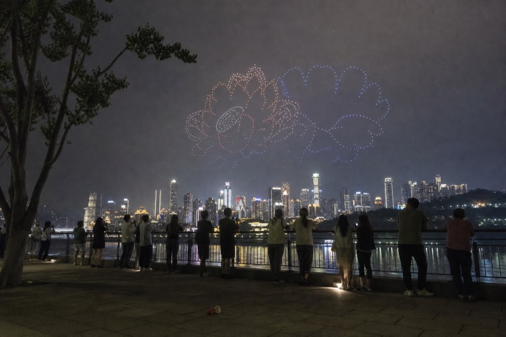 Drone light show over the Chongqing riverfront with skyline behind