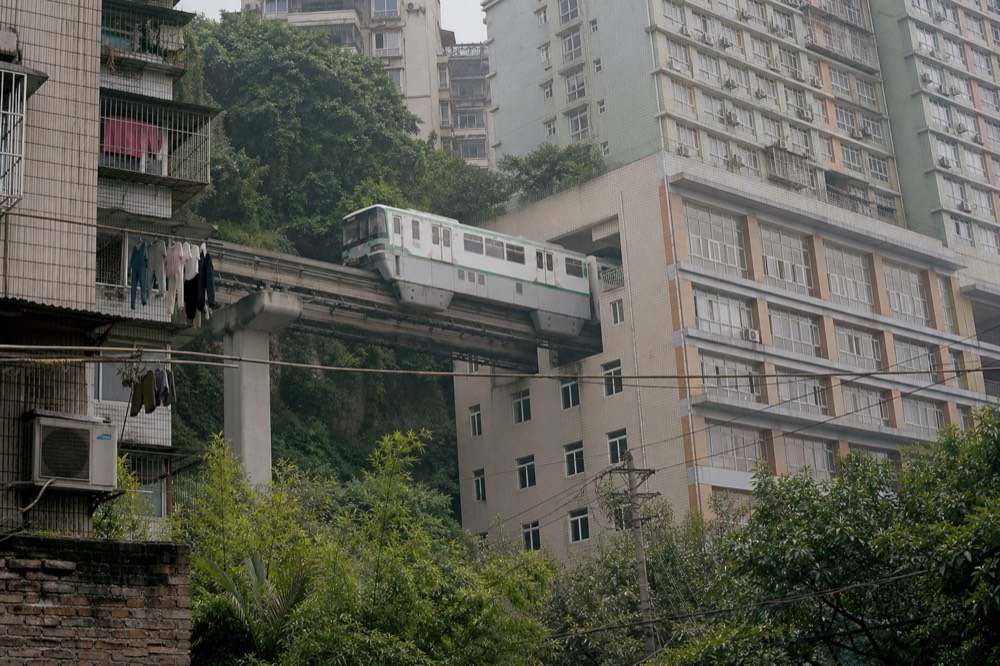 A monorail train passing through the middle floors of a residential tower above a city street