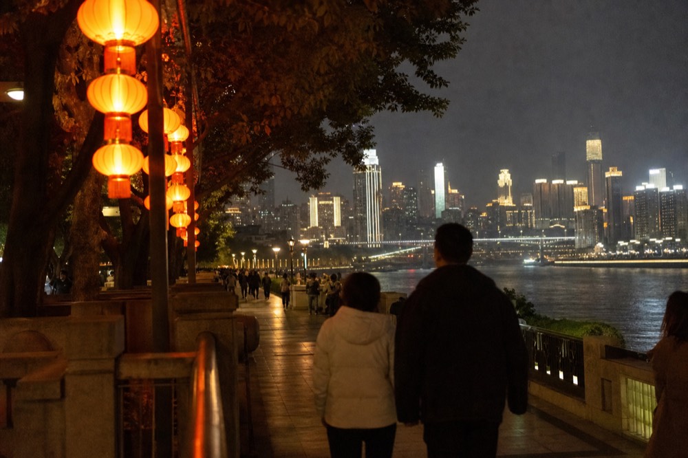 Crowded festive plaza with lanterns and illuminated towers at night