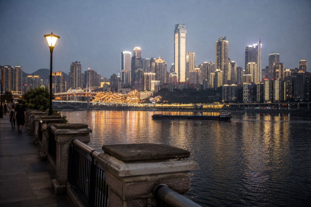 City towers illuminated at night with lights reflecting on a wide river surface