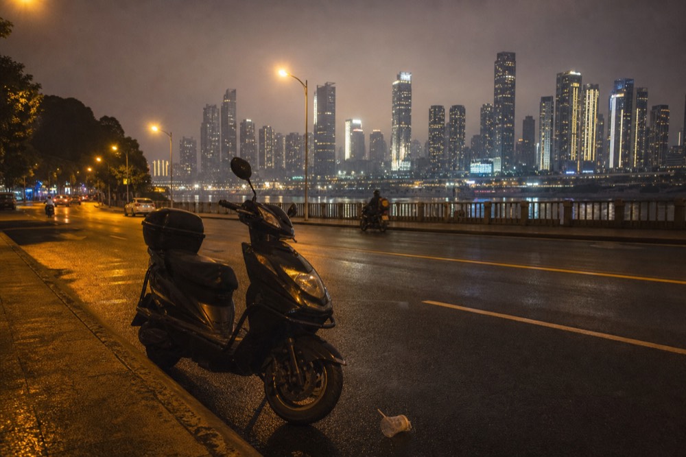 Motorcycle parked at the edge of a lit riverside road at night