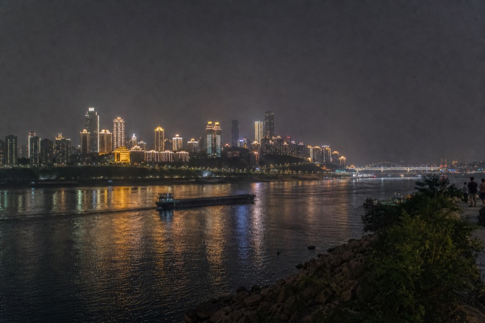 City skyline fully illuminated at night seen across a dark river