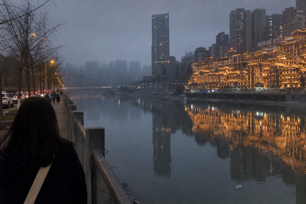 Tiered building facade doubled in a pale river at dusk