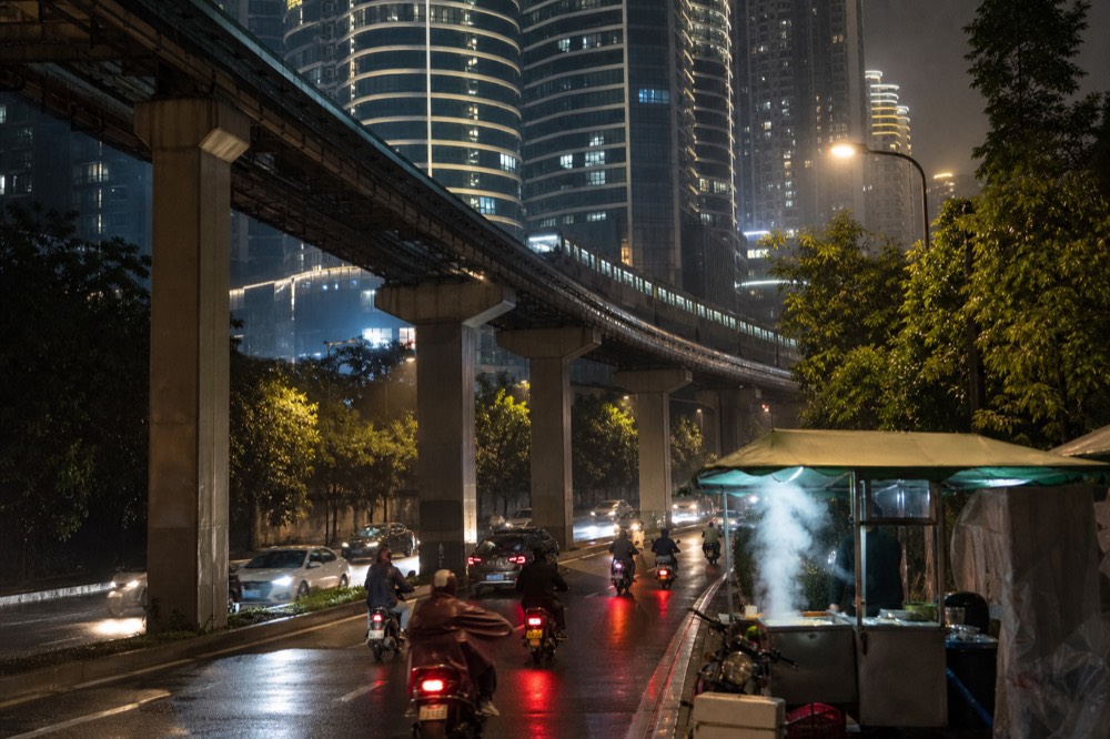 Elevated metro track curving between illuminated towers above a city street
