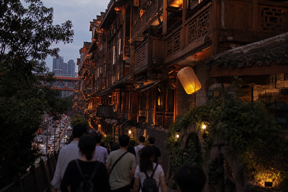 Crowded lantern-lit walkway between timber balconies in a multi-storey building