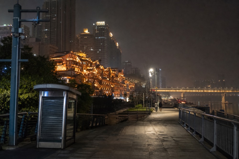 Night skyline of towers and bridges above a glowing riverside building