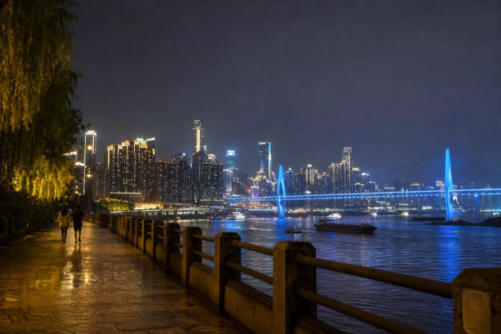 Night panorama of a densely built riverside city with illuminated bridges over a wide river