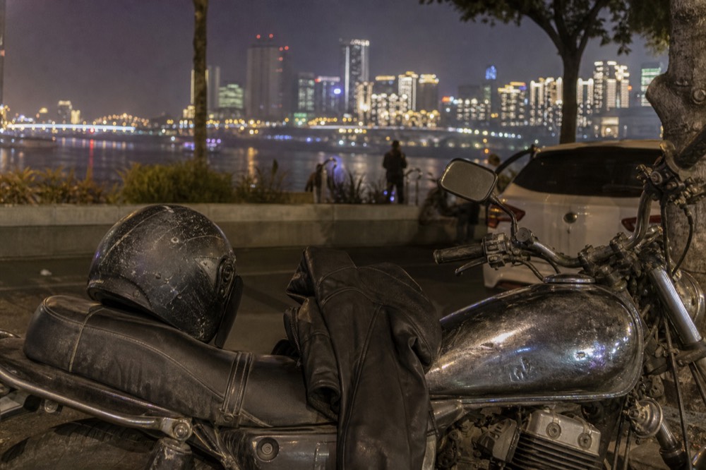 A leather jacket and helmet resting on a motorcycle seat at night