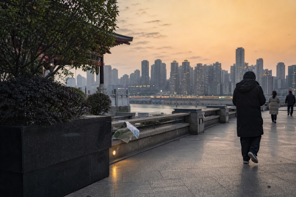 A riverside promenade walkway in the last grey daylight, before the skyline across the river lights up
