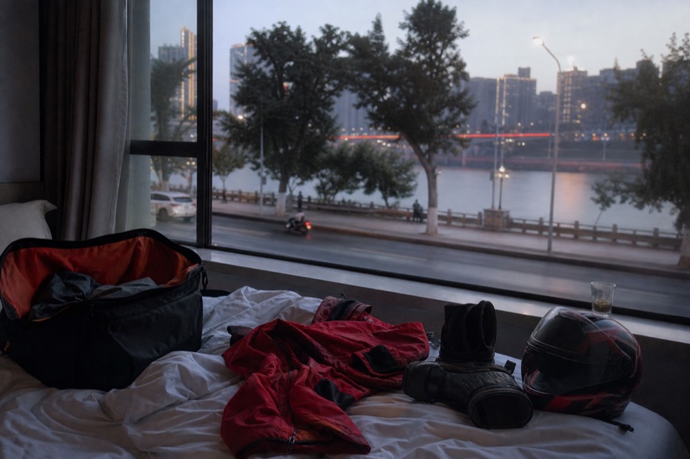 A packed weekend bag on a hotel bed with a jacket and boots laid out