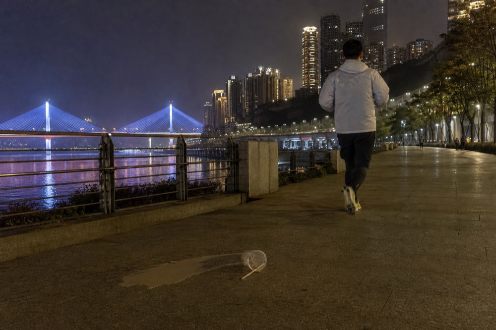 Illuminated riverside towers and bridge lights reflected in the Yangtze at night, seen from a south bank promenade