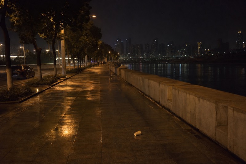 A calm section of the Chongqing riverside late at night, the promenade nearly empty once the skyline lighting across the Yangtze has gone dark.